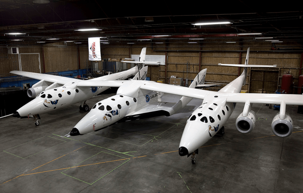 The Scaled Composites SpaceShipTwo spaceplane (central fuselage) resting under its mothership, White Knight Two, inside a hangar in Mojave, Ca., USA.