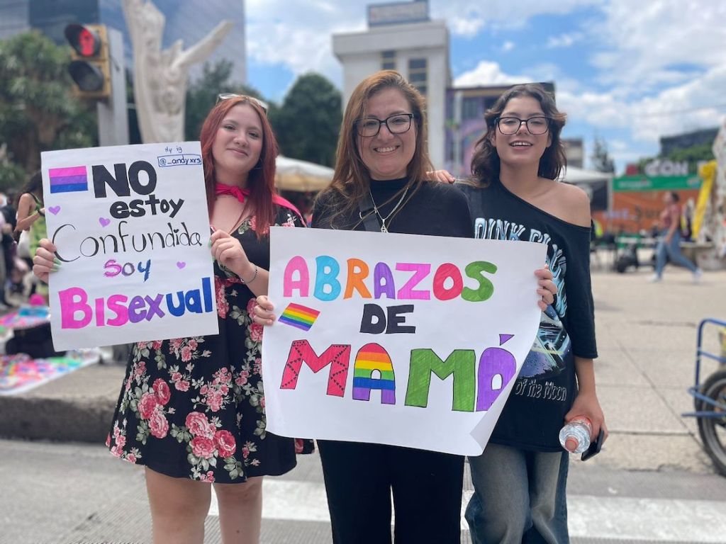 Mamá acompañada de sus hijas ofreciendo abrazos en la Marcha LGBT.